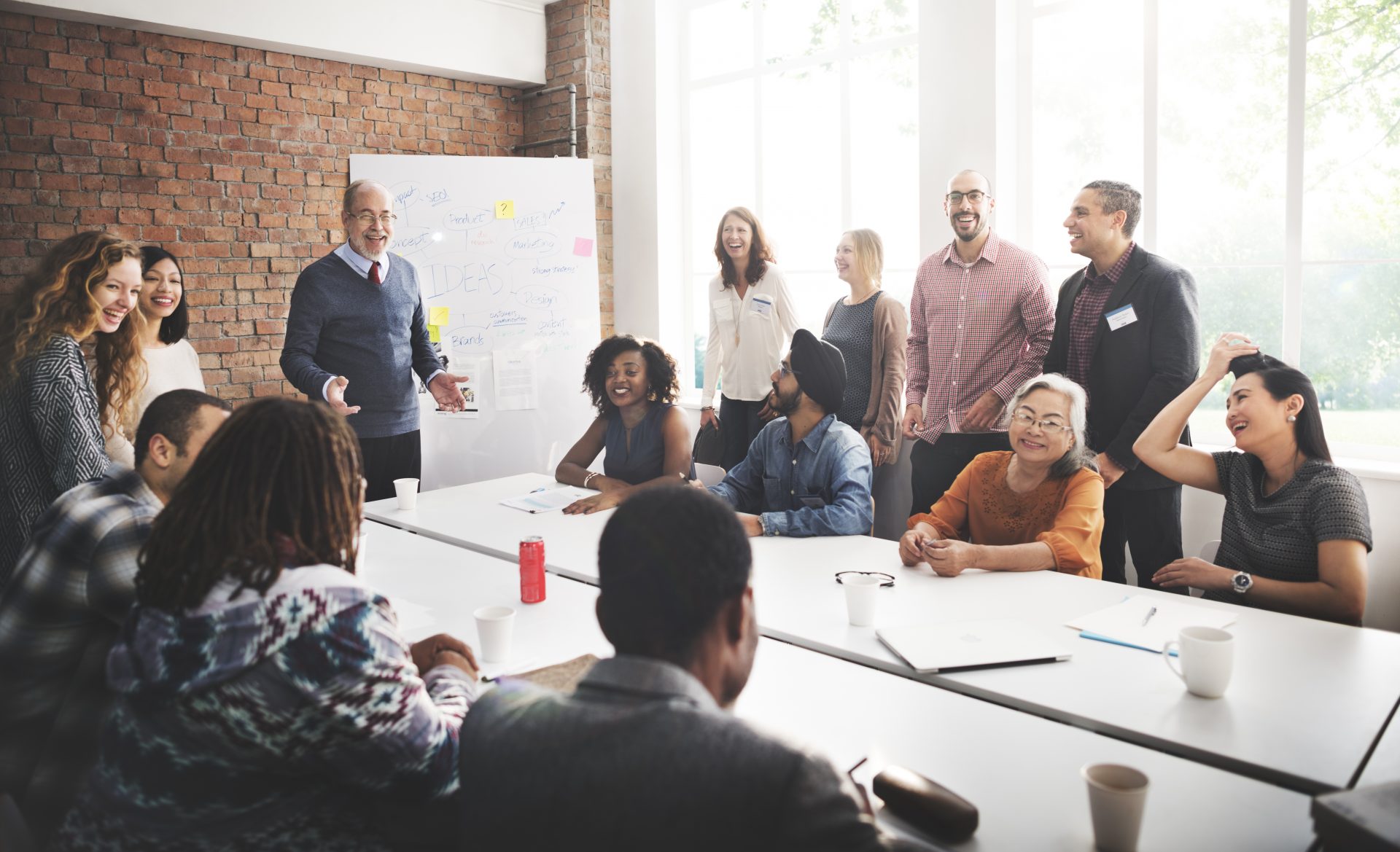 A boardroom filled with people dressed in business-casual all smile and laugh together.