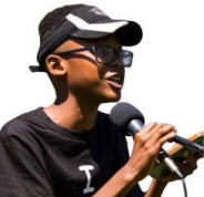 Rashad Evans, a male-presenting person, uses a microphone and looks away from the camera.