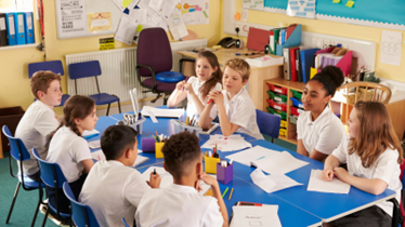 Elementary students working together at a long table on a project