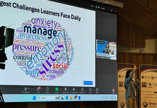 Photo of speaker onstage beside a presentation slide showing the biggest challenges learners face daily.