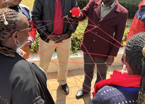 Photo of students and a teacher doing an activity involving a ball of red thread